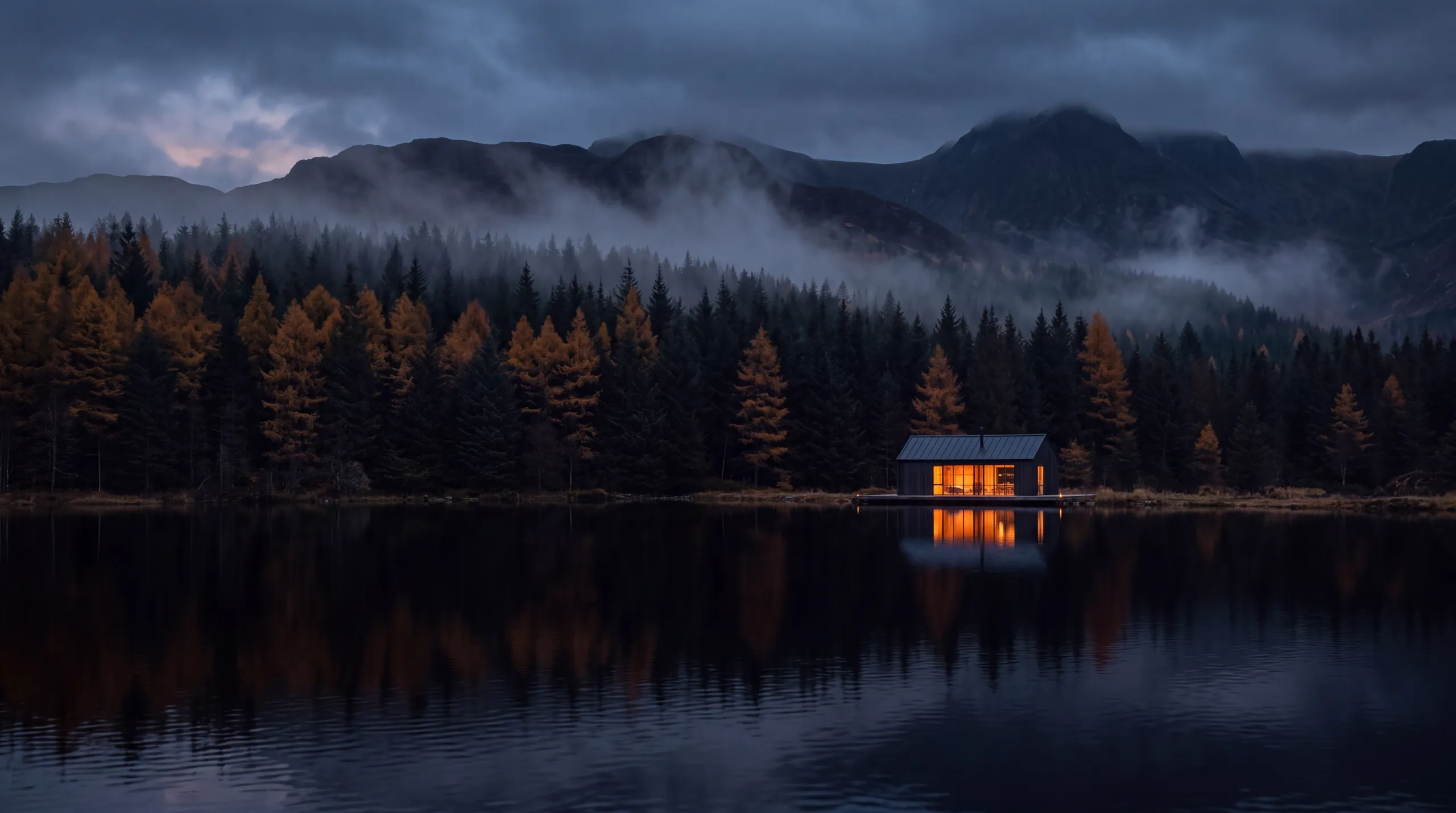 The cabin seen from across the lake at dusk, windows glowing